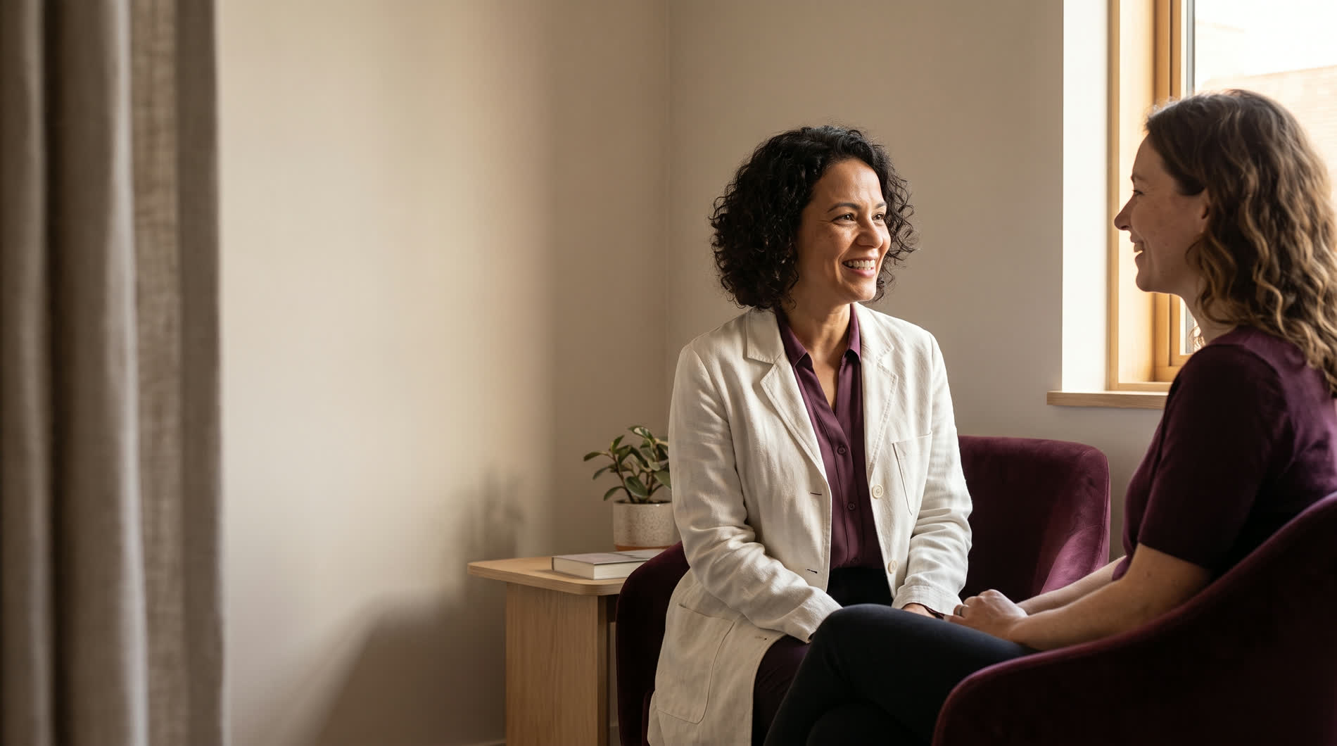 Médica e paciente conversando sentadas na sala de atendimento da clínica